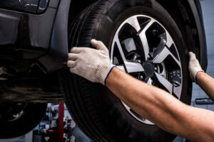 Close-up of mechanic in a car service removes a wheel from a car manually